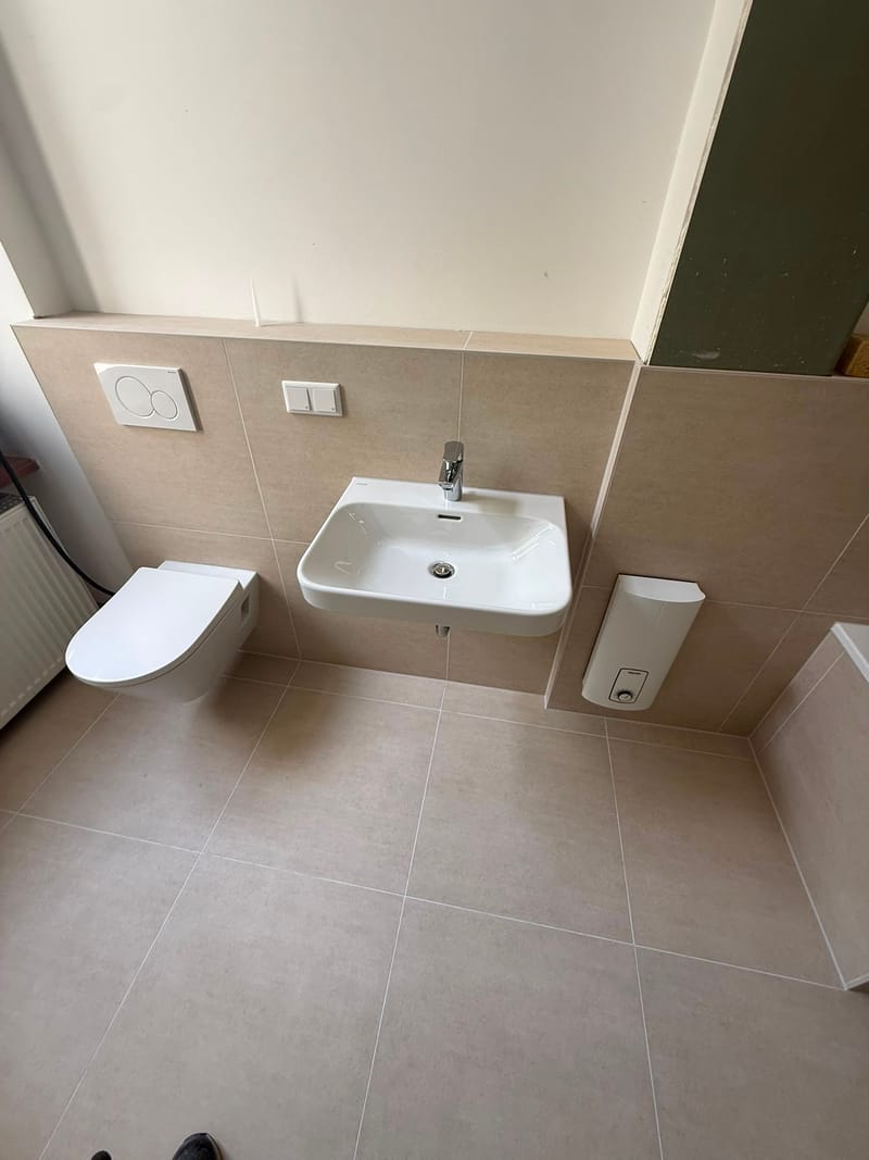Neu gefliestes Bad in Beige mit Hänge-WC, Waschbecken und Geberit-Betätigungsplatte