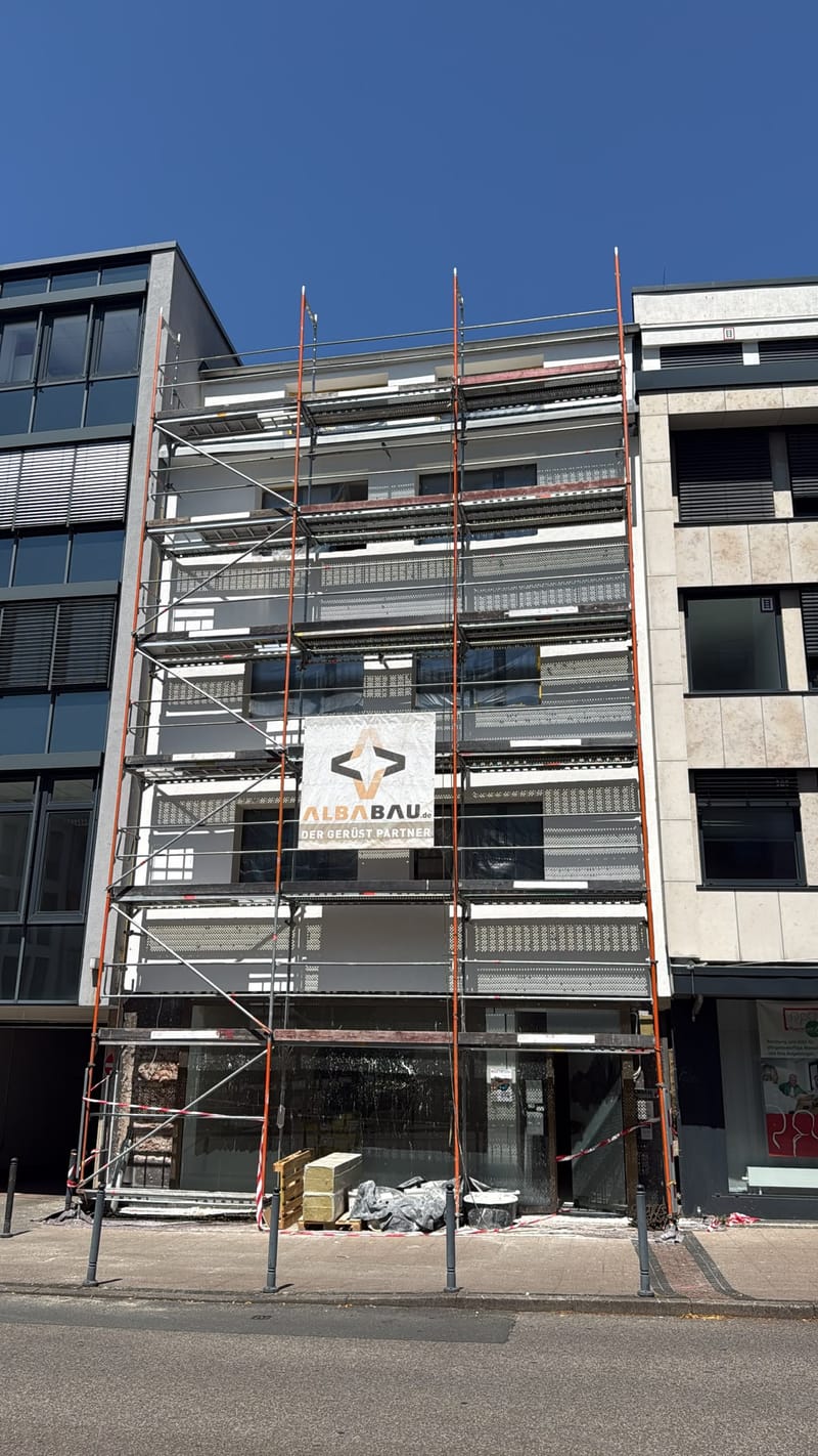 Frisch verputzte helle Fassade hinter Gerüst bei blauem Himmel
